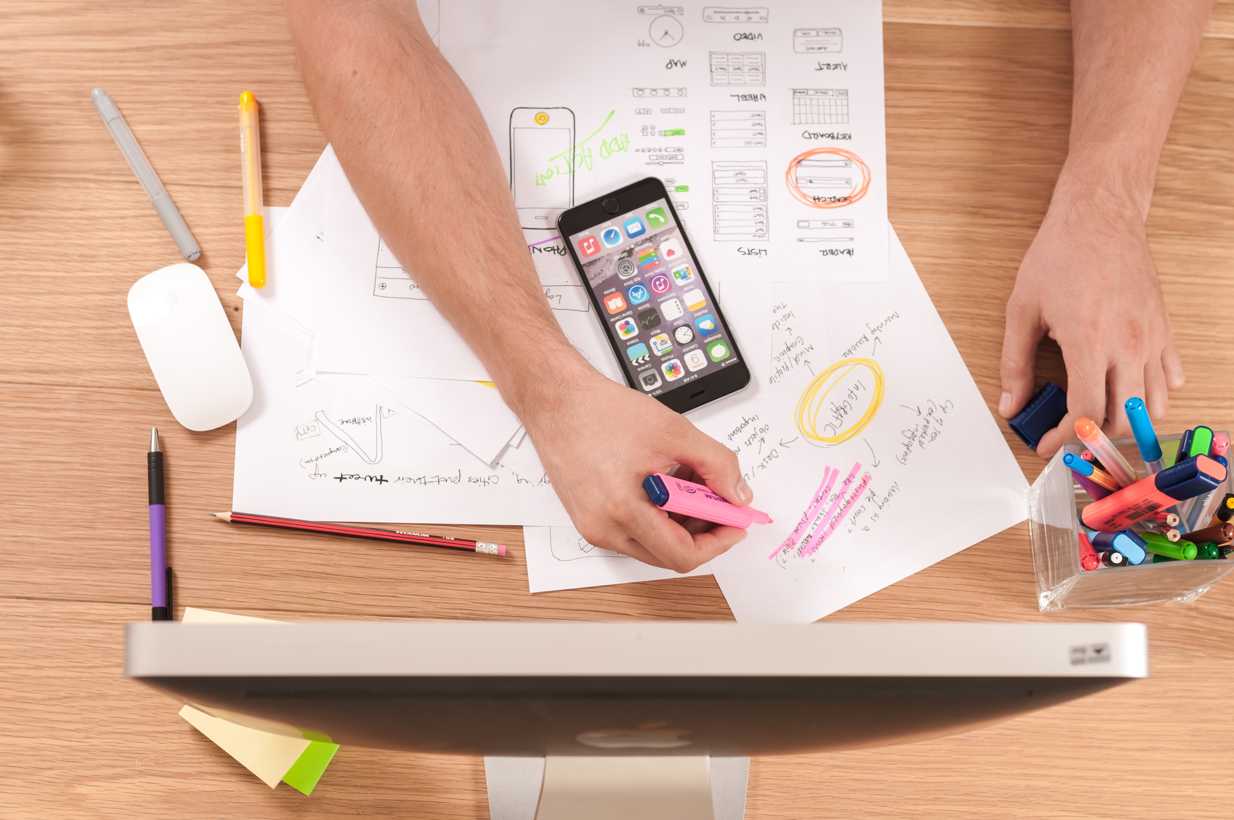 Person at desk holding a highlighter reviewing documents 